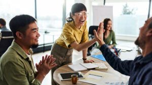 Team celebrating and high-fiving around table